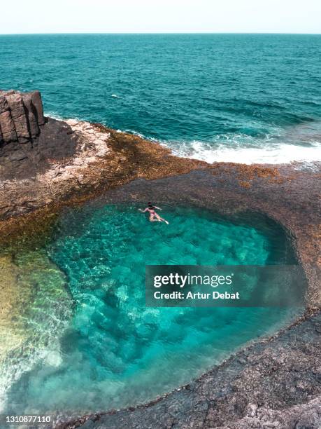 woman swimming in paradise natural pool next to the sea in the fuerteventura island. spain. piscina natural en la costa de fuerteventura durante la marea baja con aguas cristalinas. - canary stock pictures, royalty-free photos & images