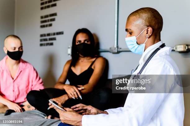 a black doctor in the home care of a transgender couple - médicos sem fronteiras imagens e fotografias de stock