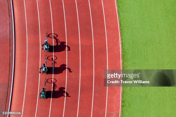 view from directly above three men wheelchair racing on a track. - racetrack ストックフォトと画像