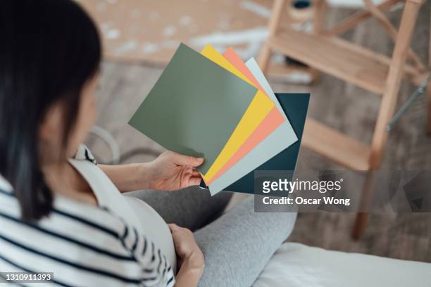 pregnant woman examining paint swatches for nurses room - pantone swatch stock pictures, royalty-free photos & images