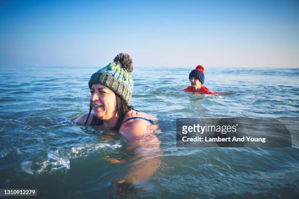 woman in a thick wooly hat winter sea swimming with her mother - thick white women fotografías e imágenes de stock