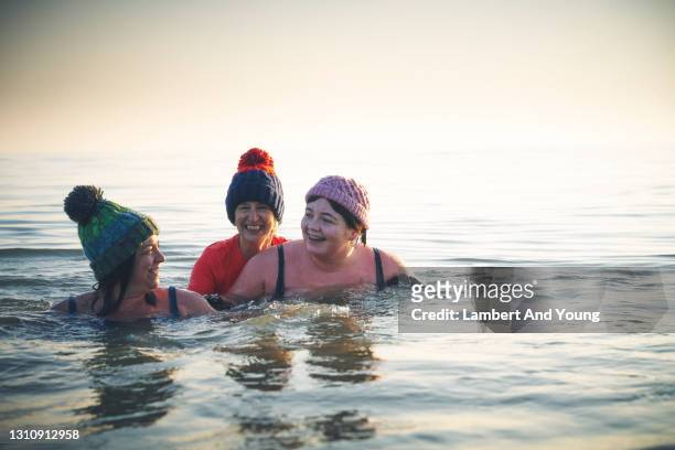 family having a moment together messing about while winter sea swimming - mature woman winter stock pictures, royalty-free photos & images