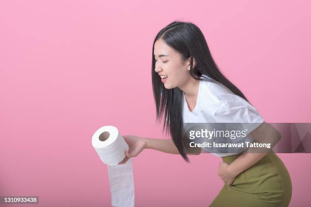 woman hand holding her crotch lower abdomen and tissue or toilet paper roll. disorder, diarrhea, incontinence. healthcare concept. - woman hemorrhoids fotografías e imágenes de stock