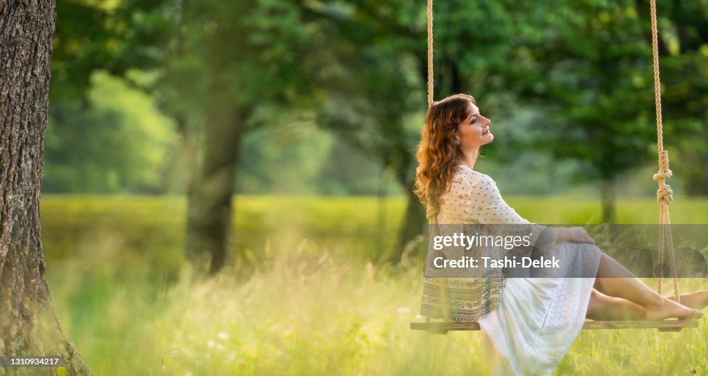 Mujer sentada en swing en el parque