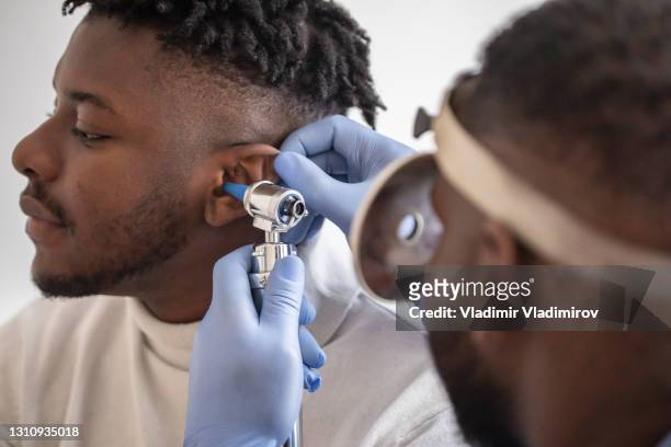 primo posto di un medico che controlla l'orecchio del suo paziente maschio - otoscope foto e immagini stock