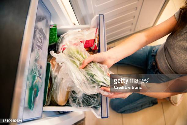 meisje dat ruw voedsel van koelkast neemt - vacuum stockfoto's en -beelden