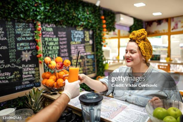 junge frau, die ihren frischen orangensaft bucht. - chubby man shopping stock-fotos und bilder