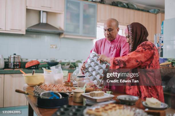 ramadan malaysian malay senior couple baking in kitchen preparing festive celebration at home celebrating hari raya - wife beater stock pictures, royalty-free photos & images