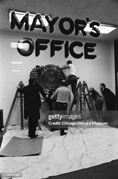 Workmen hanging the City Seal on the outer wall of the Mayor's Office, 121 North LaSalle Street, Chicago, Illinois, November 14, 1968.