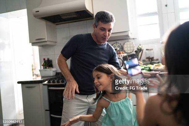 girl filming father and daughter dancing at home - real life funny stock pictures, royalty-free photos & images