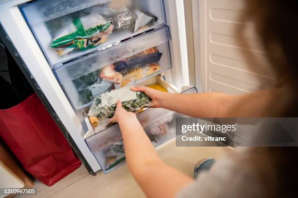 flicka tar rå mat från kylskåp - frozen food bildbanksfoton och bilder