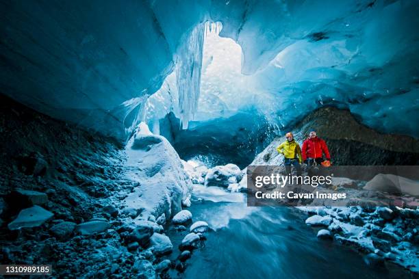 men exploring ice cave in thorsmork - iceland - spelunking stock pictures, royalty-free photos & images