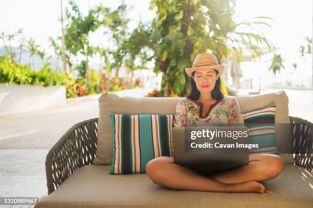 young smiling woman working on laptop in the yard of her house. - acapulco stock pictures, royalty-free photos & images