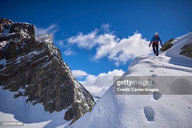 man climbing a snowy mountain on a sunny day in devero, italy. - alpinismo stock pictures, royalty-free photos & images