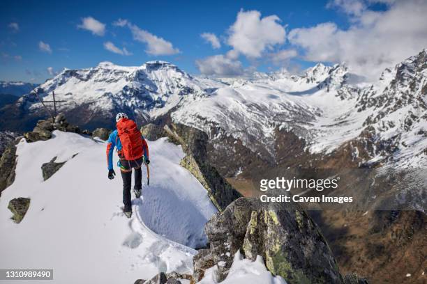 man climbing a snowy mountain on a sunny day in devero, italy. - alpinismo stock pictures, royalty-free photos & images