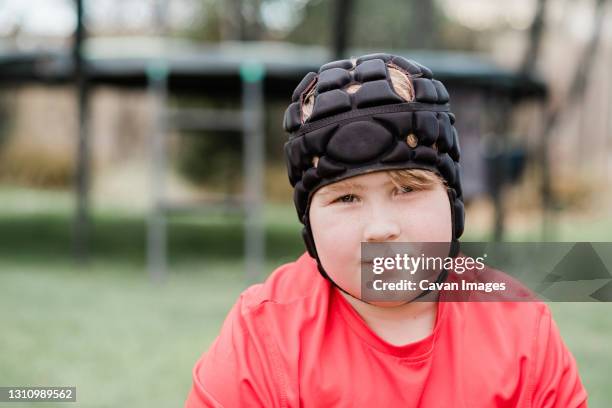 young boy wearing protection head gear in back yard - rugby league ground stock pictures, royalty-free photos & images