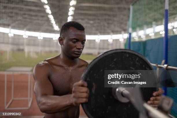 black athlete attaching weight to bar - positioned stock pictures, royalty-free photos & images