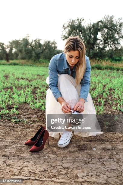 young woman changes her shoes while sitting on a chair in the field - beautiful legs in high heels stock pictures, royalty-free photos & images