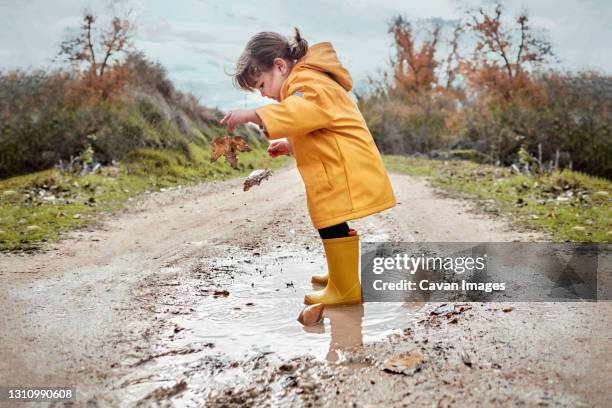 a 2 year old girl playing with a mud puddle - baby boot stock pictures, royalty-free photos & images