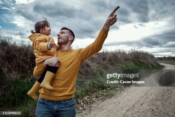 a dad pointing out something to his 2 year old daughter in natur - boots over pants stock pictures, royalty-free photos & images