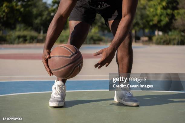 cropped black athlete dribbling basketball ball - dribbling sport fotografías e imágenes de stock