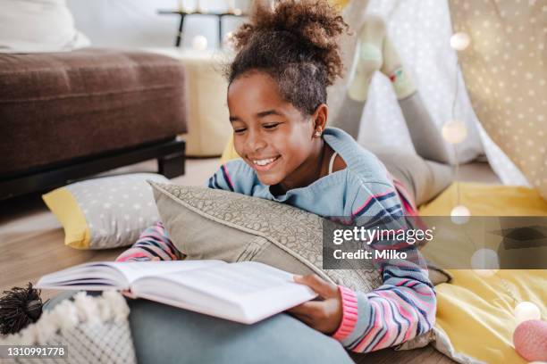 a little african american girl is reading a book at home - 8 9 years stock pictures, royalty-free photos & images