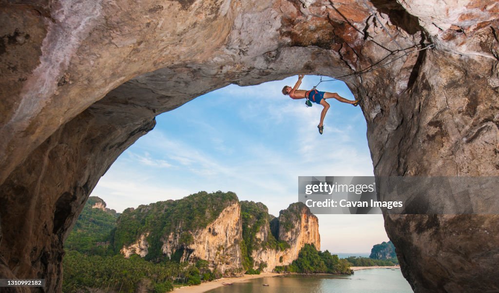 Young man climbing overhanging rock face at Tonsai beach