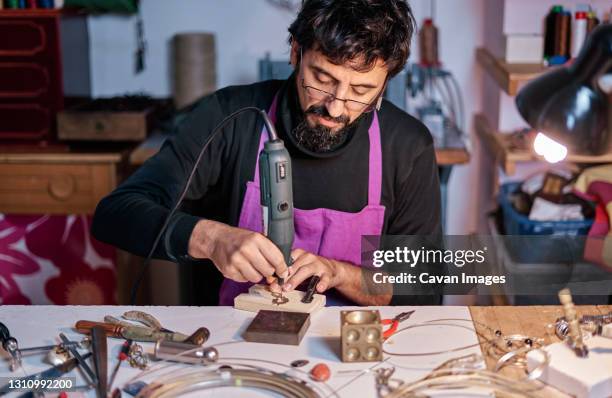 craftsman jeweler working with a drill at the work table - slijptol stockfoto's en -beelden