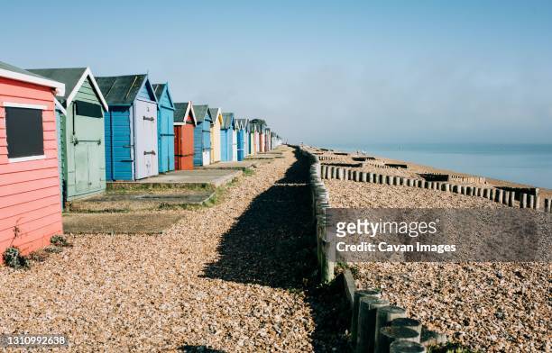 colourful huts on a pebble beach on a sunny day in england - southampton inglaterra imagens e fotografias de stock