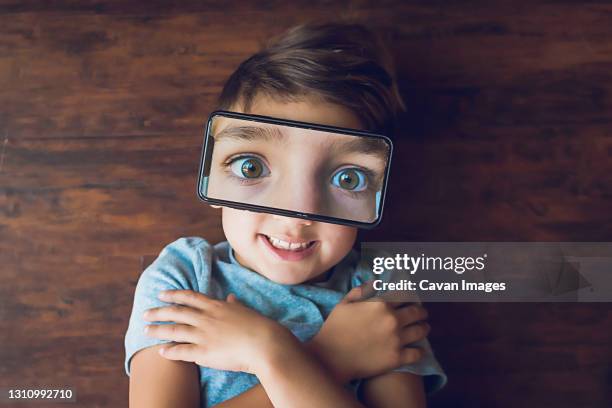 boy laying on the ground with a phone photo of his eyes on top of face - flash eyelashes stock pictures, royalty-free photos & images