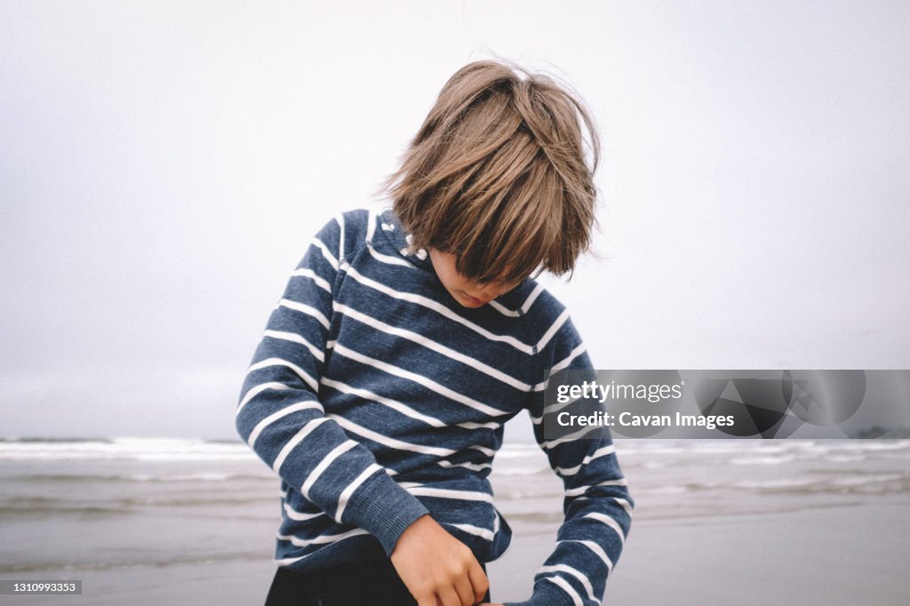 Boy in Striped Shirt with Long Hair on A Beach