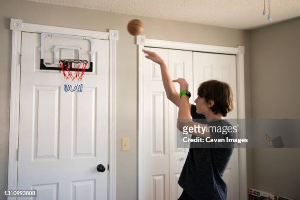 tween boy throwing a small basketball in his bedroom. - basket ball 個照片及圖片檔