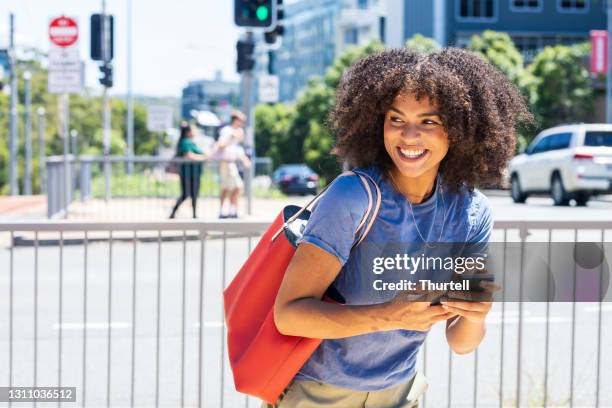 african-australian woman reacts by laughing to text message - native african ethnicity stock pictures, royalty-free photos & images