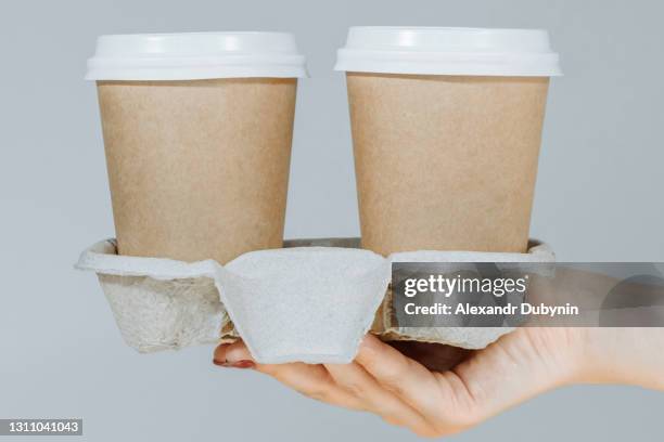 two brown disposable coffee cups on a cardboard rack isolated on a gray background. hygienic cooking or home delivery concept. banner, template, copy space - takeaway coffee stockfoto's en -beelden