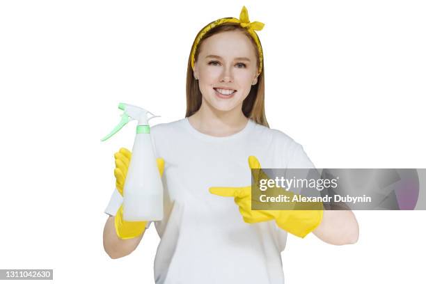 young girl in yellow cleaning gloves and with a cleaning spray on white isolated background copy space. happy woman showing finger to spray - stereotypical housewife stock-fotos und bilder