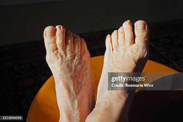 feet of old woman against dark background - bare feet stock pictures, royalty-free photos & images