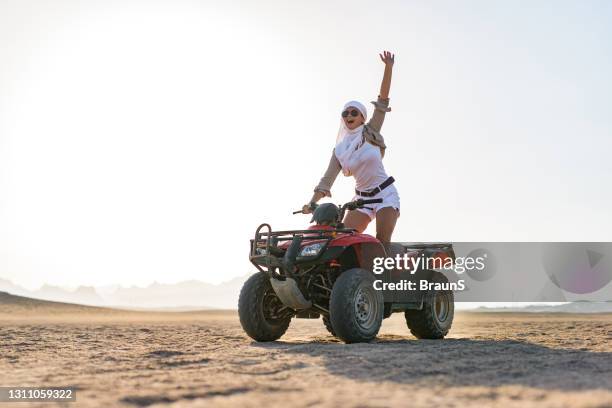 glückliche frau fährt quad-bike in der wüste. - screaming happy in car stock-fotos und bilder