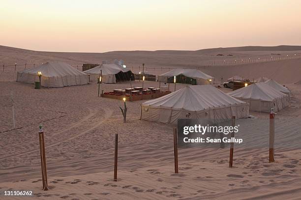 The sun sets over a desert camp of tents for tourists on October 30, 2011 near Umm Sa'id, Qatar. Camel safaris and four-wheel drive tours of the...