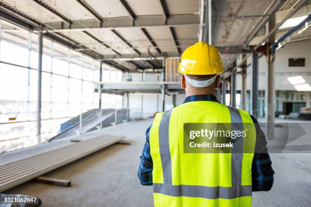 operaio edile in un cantiere interno - indumento fluorescente foto e immagini stock