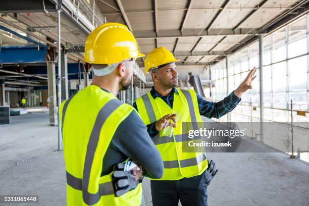 workers at an indoor construction site - builders uk stock pictures, royalty-free photos & images