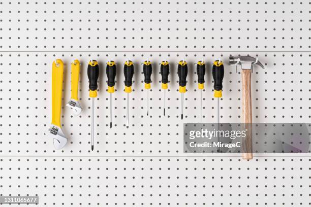 hand tools hanging on pegboard - schraubenzieher stock-fotos und bilder