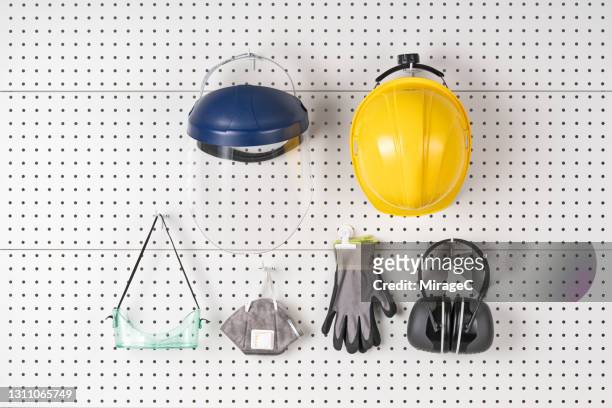 construction safety equipment hanging on pegboard - roupa desportiva de protecção imagens e fotografias de stock