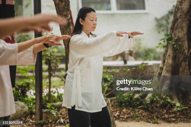 senior asian woman practicing tai chi with other people - woman and tai chi stock pictures, royalty-free photos & images