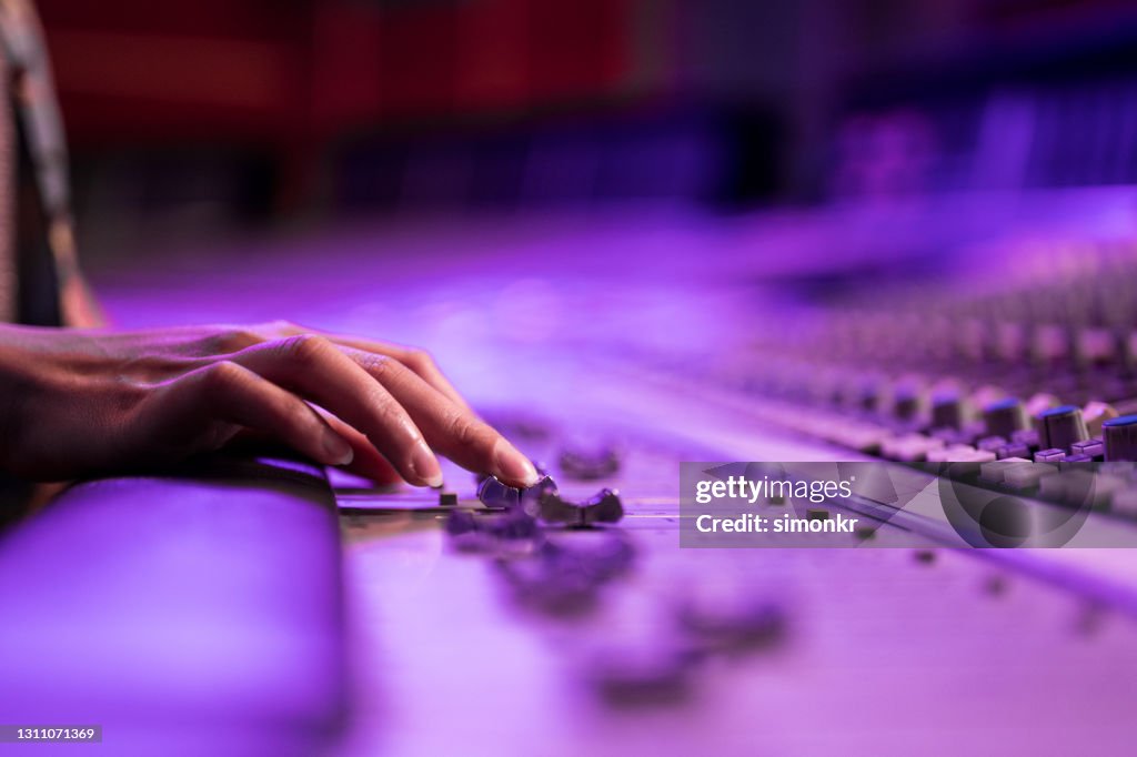 Woman's hand adjusting buttons on audio mixer