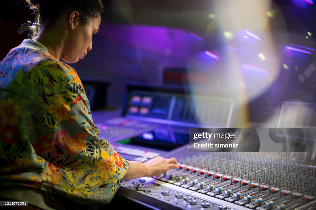 Female musician adjusting knob on audio mixer