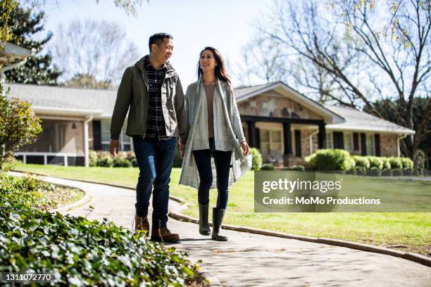 married couple walking on pathway in front of home - mann frontal ganzkörper jacket stock-fotos und bilder