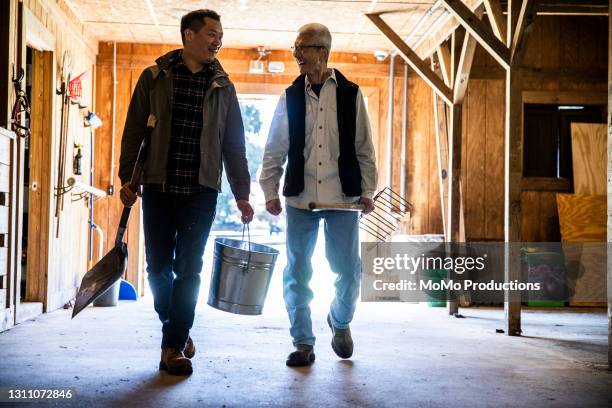 senior father and adult son walking through barn - stone mountain stock pictures, royalty-free photos & images