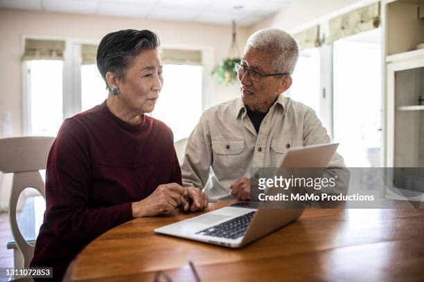 senior couple using laptop computer at home - older asian couple stock pictures, royalty-free photos & images