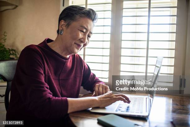 senior woman using laptop computer at home - phone scam stock-fotos und bilder