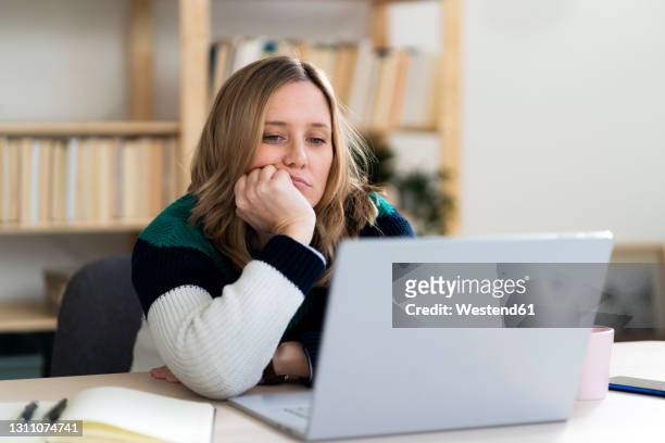 woman with hand on chin staring at laptop - boredom 個照片及圖片檔